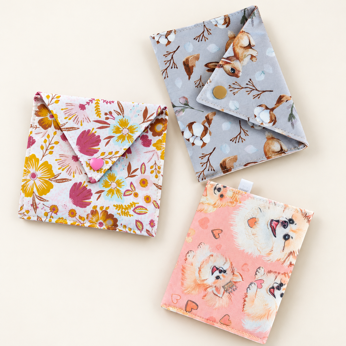Drie stoffen cadeauenvelopjes met bloemen-, konijnen- en hondenprint, als voorbeelden van het DIY-naaipakket.