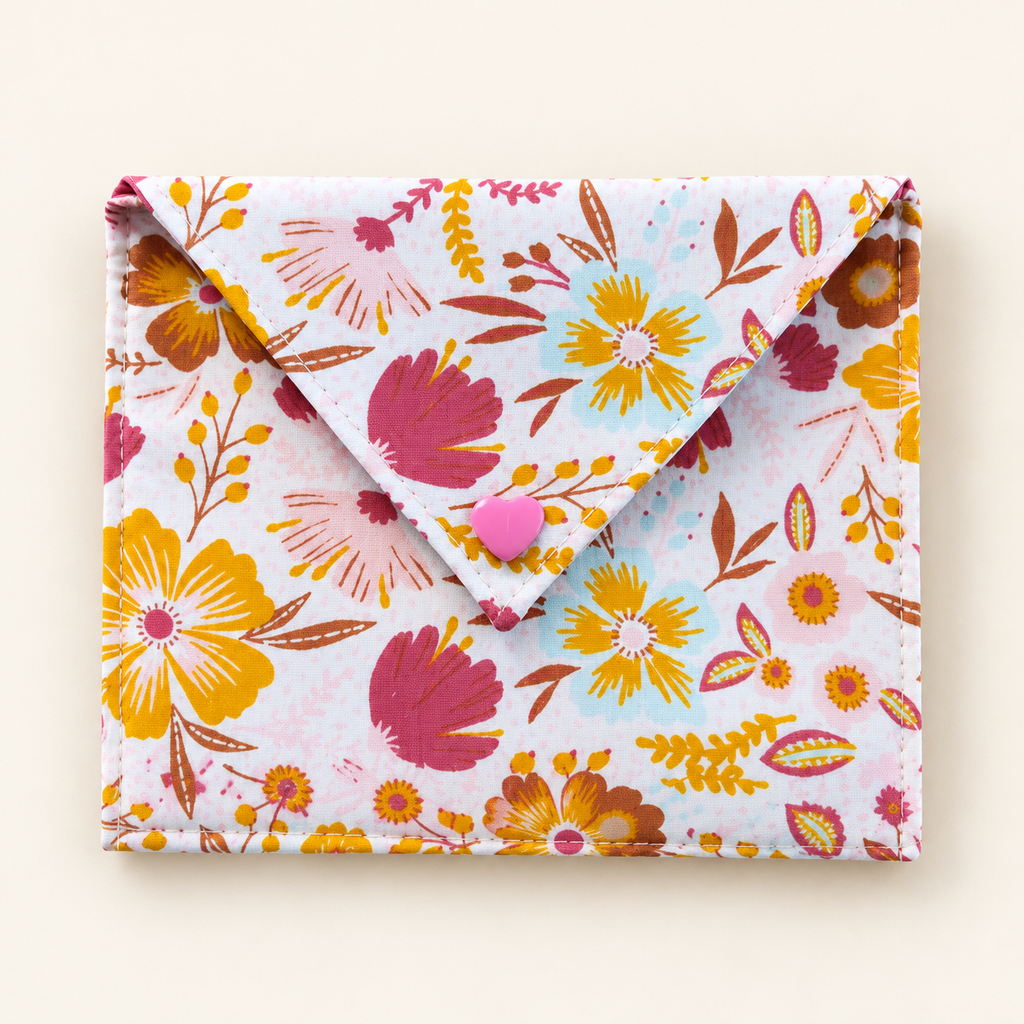 Stoffen cadeauenvelop met kleurrijke bloemenprint en roze hartvormige drukknoop, gemaakt met het DIY-naaipakket.