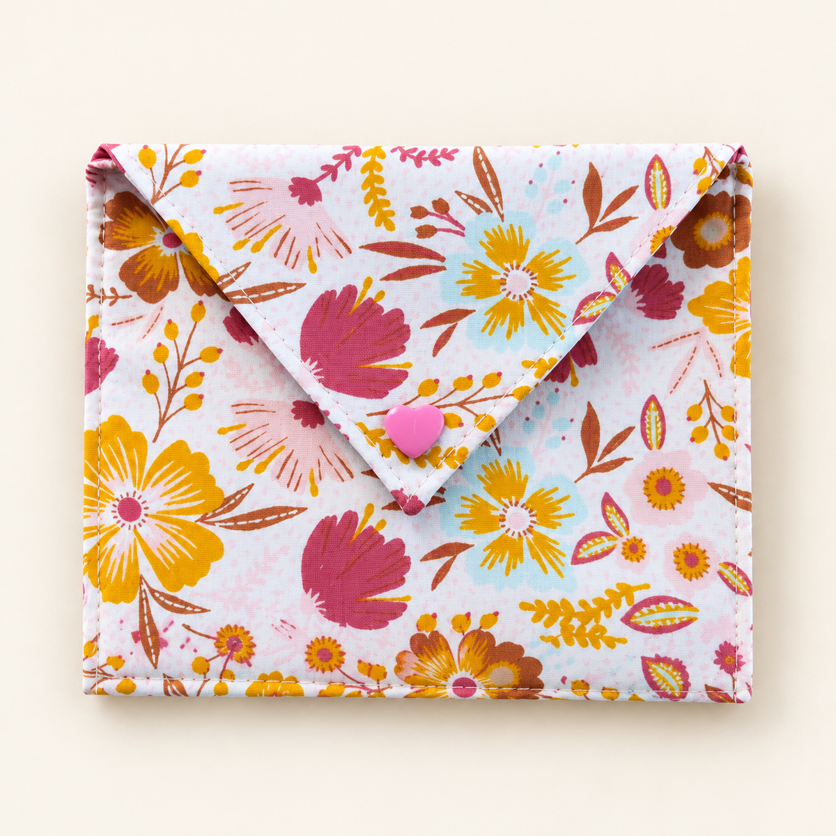 Stoffen cadeauenvelop met kleurrijke bloemenprint en roze hartvormige drukknoop, gemaakt met het DIY-naaipakket.