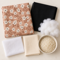 Materiaalpakket voor een deurstopper met roze bloemenstof, zwarte canvas, versteviging, balenkatoen, rijst en fiberfill.