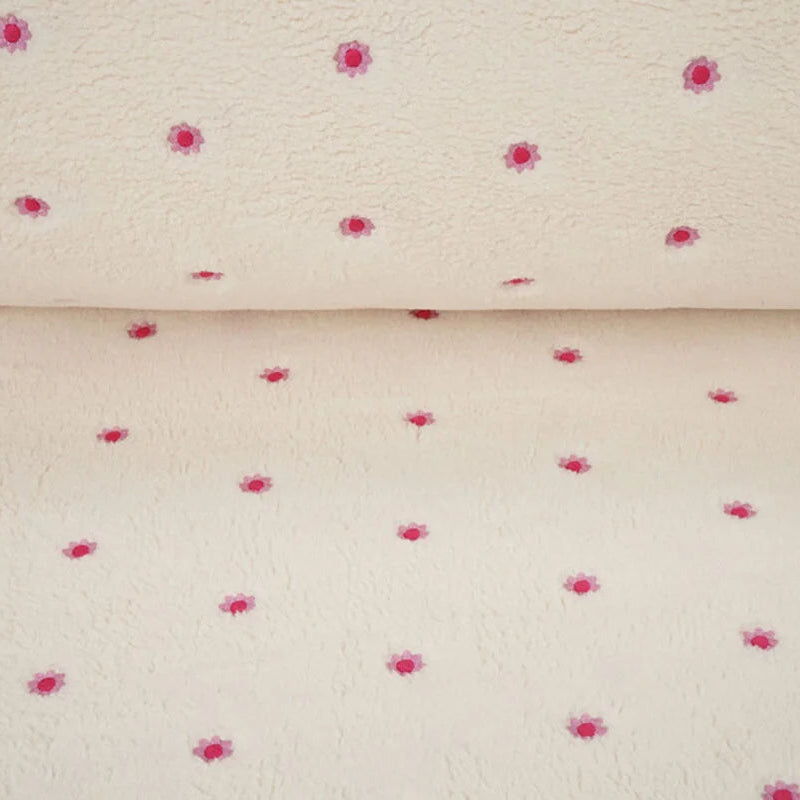 Detail van zachte crème teddy fleece met geborduurde roze bloemetjes