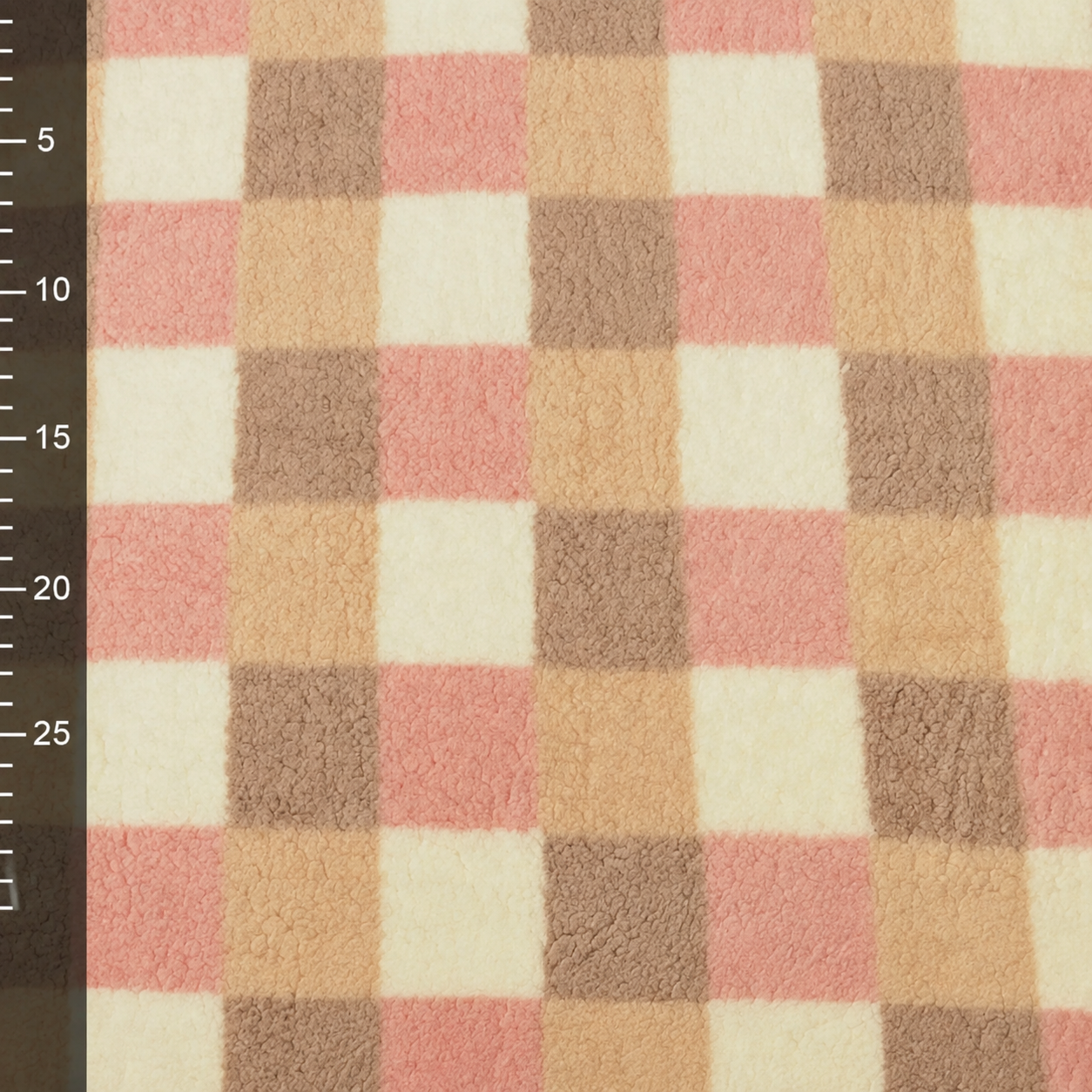 Detail van geruite teddy fleece in crème, zachtroze en taupe