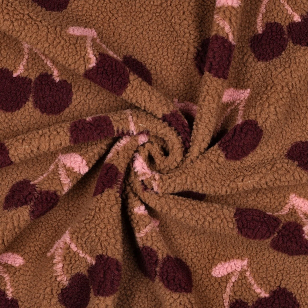 Detail van zachte bruine teddy stof met bedrukte kersen